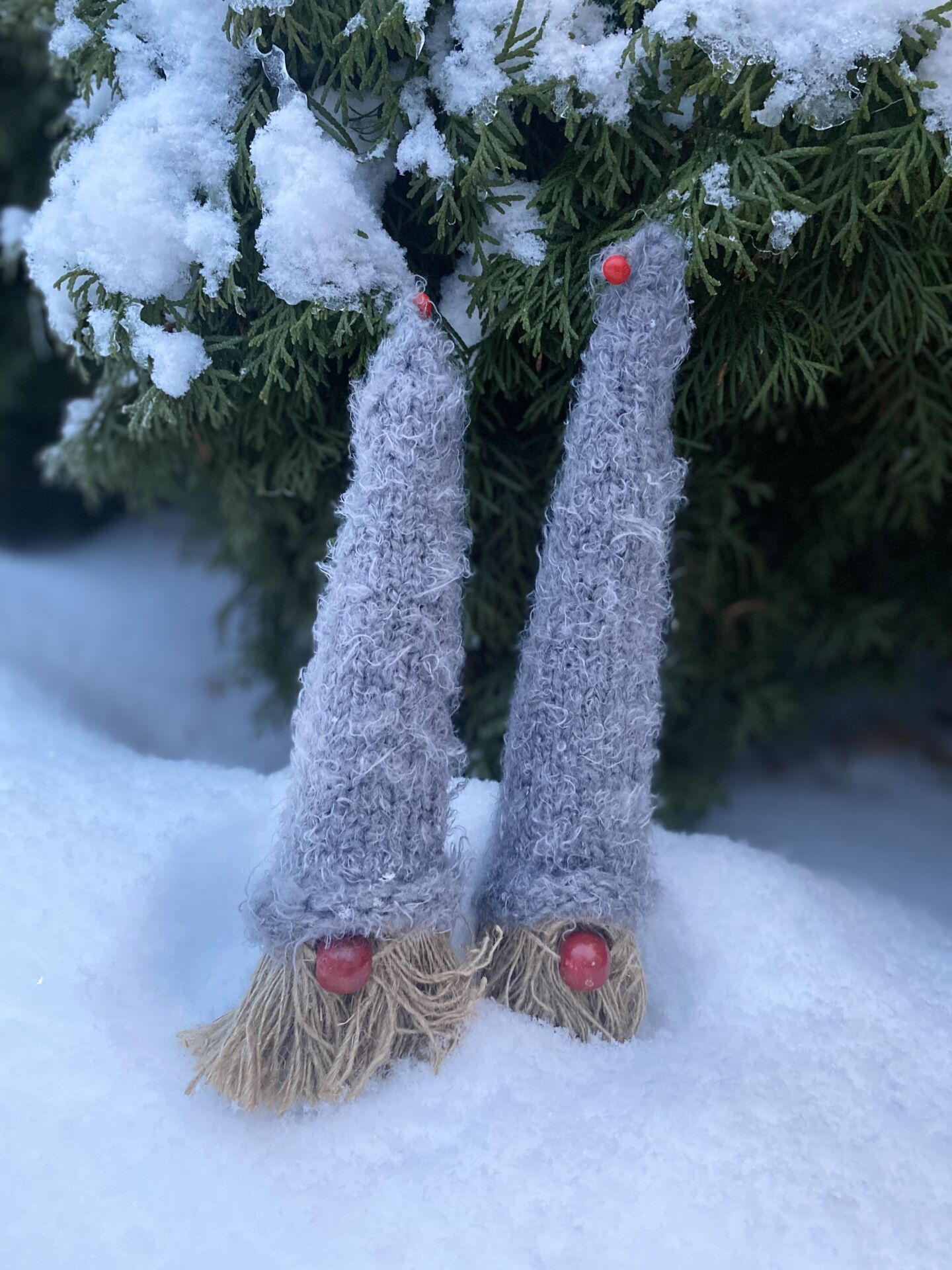 Itsetehtyjä joulutonttuja lumisessa maisemassa.